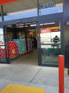 The main entrance to Grocery Outlet is an automatic double door. There are large glass windows on both sides of the door.